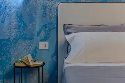 a bed with a pair of glasses and a book on a side table at Le Carte in Castellammare del Golfo
