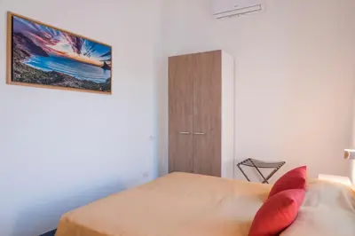 a bedroom with a bed with red pillows and a cabinet at GuestHost - La Giara - Villa with Swimming Pool and Parking in Castellammare del Golfo
