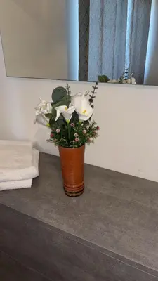 a vase with flowers on a counter in a bathroom at Costanza House in Palermo