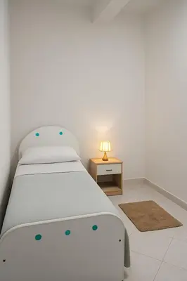 a white bedroom with a bed and a table at Appartamento Matteo in Trappeto