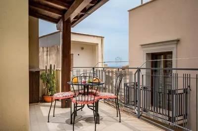 a patio with a table and chairs on a balcony at Casa Dolce Casa in Castellammare del Golfo