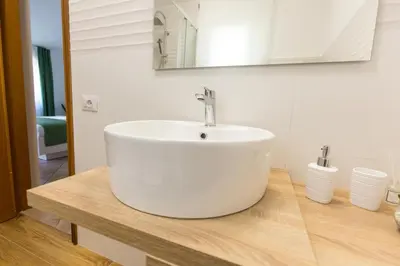 a bathroom with a white sink on a wooden counter at Isola Suite in Isola delle Femmine