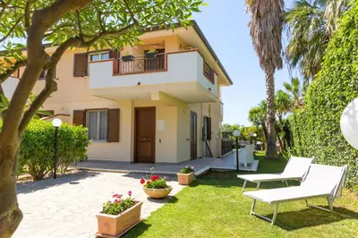 a house with two white benches in the yard at Isola Suite in Isola delle Femmine
