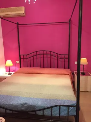 a bedroom with a bed with a pink wall at Villa La Palmetta a San Vito lo capo in San Vito lo Capo