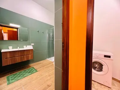 a bathroom with a sink and a washing machine at Orange House in Isola delle Femmine