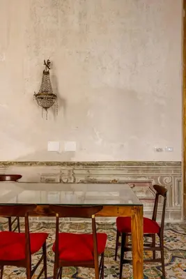 a dining room with a table and red chairs at Palazzo Sant'Isidoro by DomuSicily in Palermo