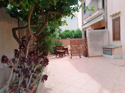 a courtyard with a tree and a table and chairs at Sanvitotour - Appartamento Amaca in San Vito lo Capo
