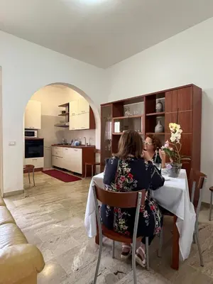 two women sitting at a table in a kitchen at Casa Finuzza in San Vito lo Capo