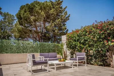 a patio with two chairs and a table and a bush at Villa Spada con ampi spazi esterni in San Vito lo Capo