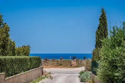 a road with a fence and the ocean in the background at Villa Spada con ampi spazi esterni in San Vito lo Capo