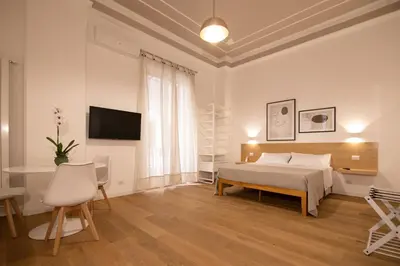 a white bedroom with a bed and a table and chairs at Villareale47 Luxury Suites & Rooms in Palermo