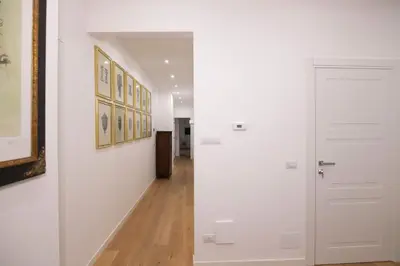 a hallway with a white door and paintings on the walls at Villareale47 Luxury Suites & Rooms in Palermo
