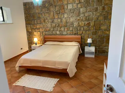 a bedroom with a bed and a stone wall at PANORAMIC VIEW - Sabrina's house in Altavilla Milicia
