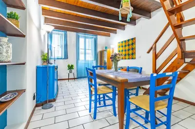 a dining room with a wooden table and blue chairs at GuestHost - The Traveller's House - Palermo Station Apartments in Palermo