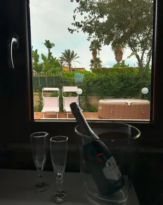 a bottle of wine in a glass next to two glasses at Chalet Seaview by AR Group Hotels in Isola delle Femmine