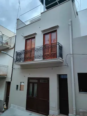 a white building with a balcony and a door at Casa Fugardi in Castellammare del Golfo