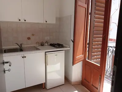 a kitchen with white cabinets and a sink and a window at Casa Fugardi in Castellammare del Golfo