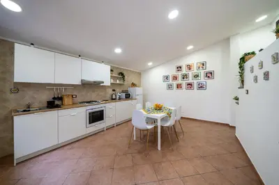 a kitchen with white cabinets and a table and chairs at Palermo e Dintorni - Valentino Apartment in Palermo