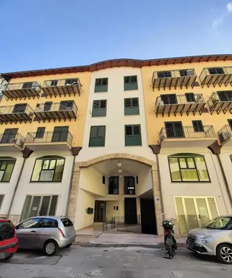 a large building with cars parked in a parking lot at Stella del Centro Apartment in Palermo