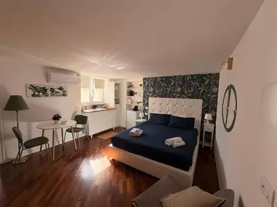 a bedroom with a bed and a table and a kitchen at Calvello studio apartment in Palermo