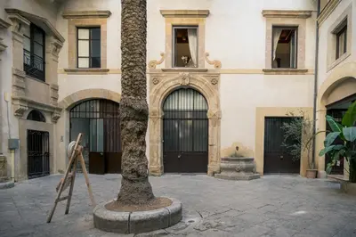 a palm tree in front of a building at Palazzo Santa Ninfa - Luxury Mansion in Palermo