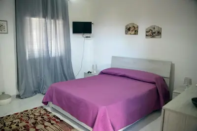 a bedroom with a purple bed and a window at Villino Anna e Pippino in Calatafimi