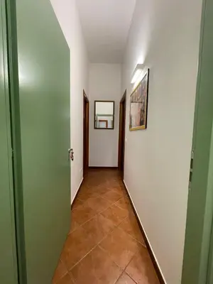 a hallway with green doors and a tile floor at Vittorosa House in Palermo