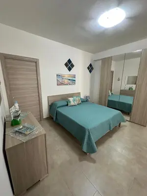 a bedroom with a green bed and a table at Sogno d'estate in Isola delle Femmine