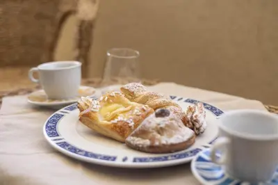 two pastries on a plate on a table with two cups at Oltre il Mare Trabia in Trabia