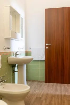 a bathroom with a sink and a toilet and a wooden door at Oltre il Mare Trabia in Trabia