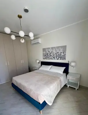 a bedroom with a large bed and a chandelier at NOVIMO Comfort Apartment with elevator & secure privat parking in Terrasini