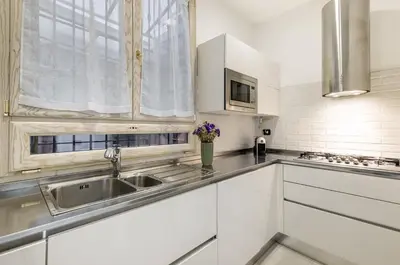 a kitchen with white cabinets and a sink at GuestHost - La Cala Sea View Apartment with Balconies in Palermo