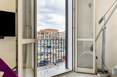 a room with a window with a view of a city at GuestHost - La Cala Sea View Apartment with Balconies in Palermo