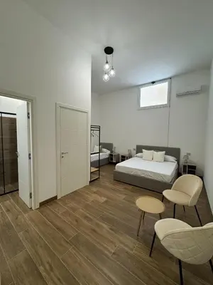 a bedroom with a bed and two chairs and a table at Casa Bedda - INTERA CASA CON 3 CAMERE CON BAGNO PRIVATO, ARIA CONDIZIONATA E NO ZTL/ENTIRE APARTMENT WITH 3 BEDROOMS WITH PRIVATE BATHROOM, AIRCON AND NO LTZ in Castellammare del Golfo