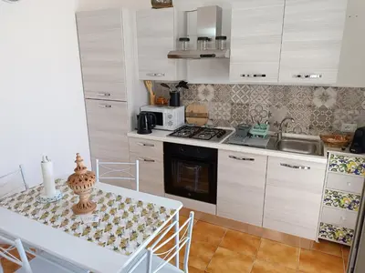 a kitchen with white cabinets and a table and a microwave at Le Tremar Carini Poseidon in Carini