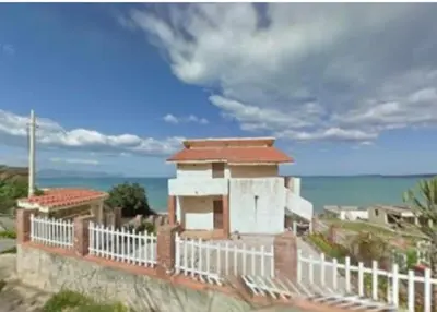 a building with a white fence next to the ocean at Sizilien 2 in Trappeto