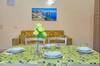 a table with plates and a vase of flowers on it at Casa Maria Stella Scopello in Scopello