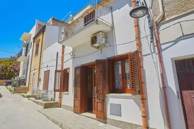a white building with wooden doors and a street light at Casa Maria Stella Scopello in Scopello