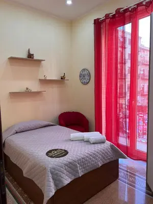 a bedroom with a bed and a window with red curtains at Ninohouse in Palermo