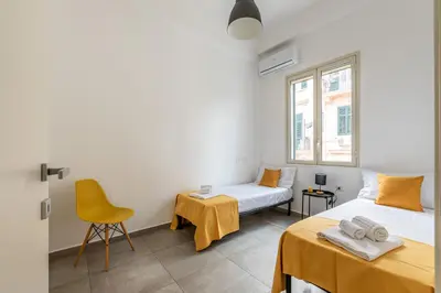 a bedroom with two beds and a yellow chair at Lumar Sicilia - Magione in Palermo