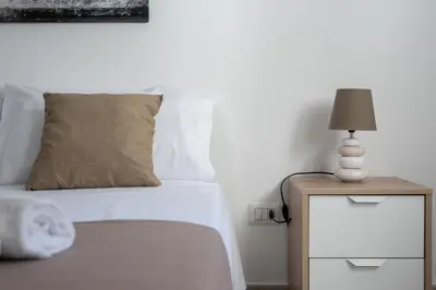 a white bed with a lamp on a night stand at Lumar Sicilia - Quaroni in Palermo