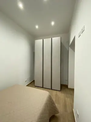 a bedroom with a bed with white walls and wooden floors at Casa Nonna Lina in Isola delle Femmine