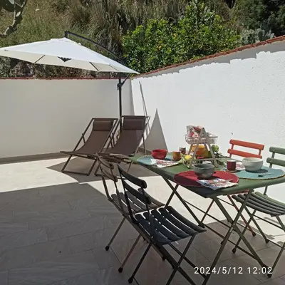 a table with chairs and an umbrella on a patio at Mediterraneo Rooms in Castellammare del Golfo