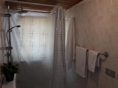 a shower with a white shower curtain in a bathroom at La casa di Ross in Casteldaccia