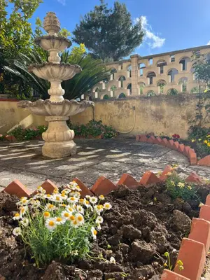 a fountain in the middle of a garden with flowers at Nonna Ciccina’s House in Vita