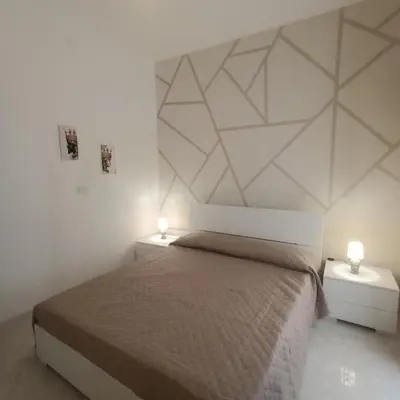 a white bedroom with a bed and two night stands at Sole e mare 1 in Isola delle Femmine