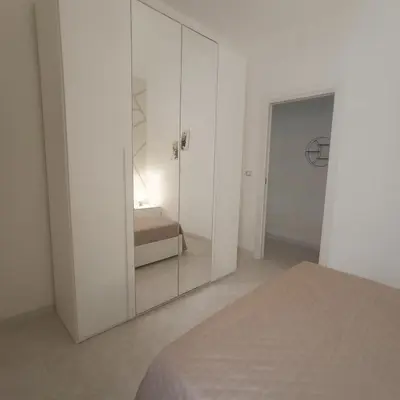 a white bedroom with a mirrored cabinet with a bed at Sole e mare 1 in Isola delle Femmine