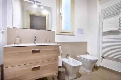 a bathroom with a sink and a toilet and a mirror at Cassari Maisons in Palermo