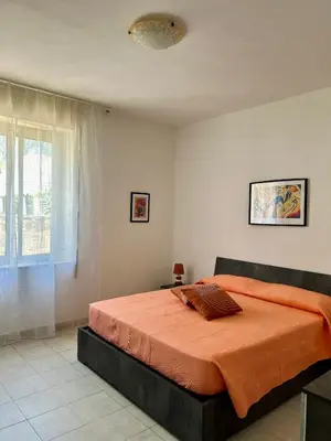 a bedroom with a large bed with an orange blanket at Casa Iohana in San Vito lo Capo