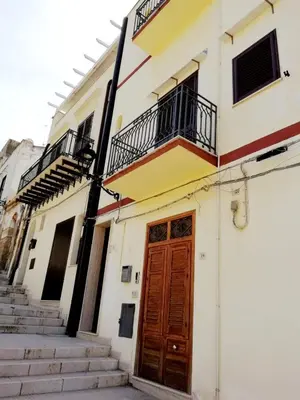 a building with a wooden door and stairs at Casa Marina con vista sul castello in Castellammare del Golfo